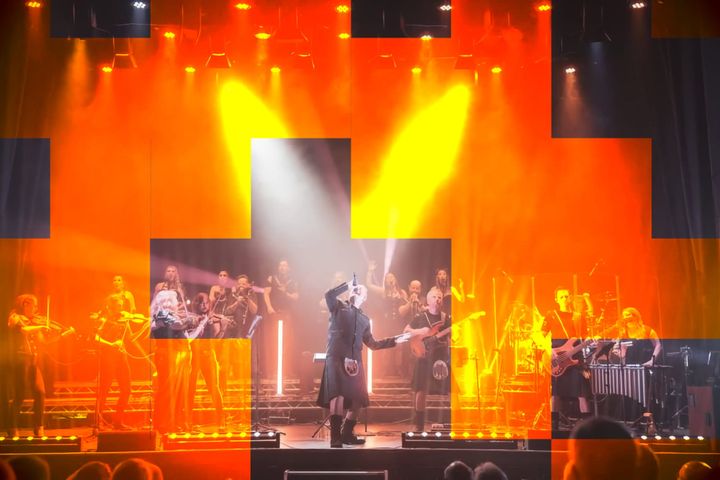Symphonix Rock Orchestra perform on stage with bright yellow lights and a full band setup.