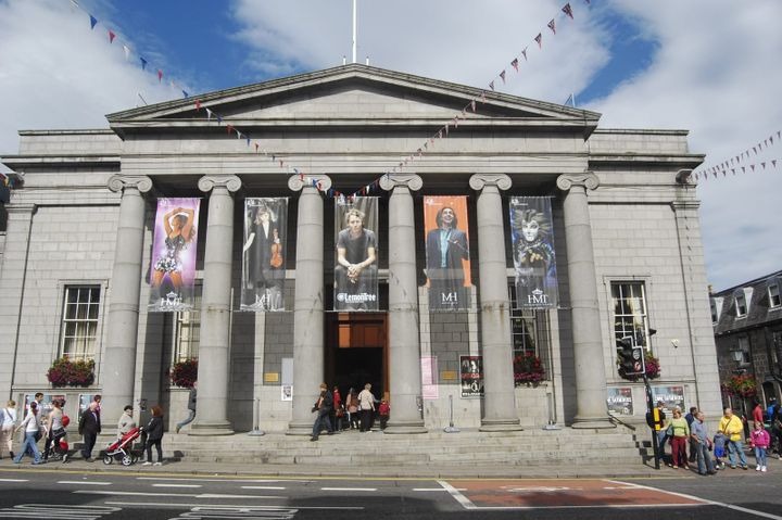 Front view of Aberdeen Music Hall, with tall stone columns, event banners, and people entering.