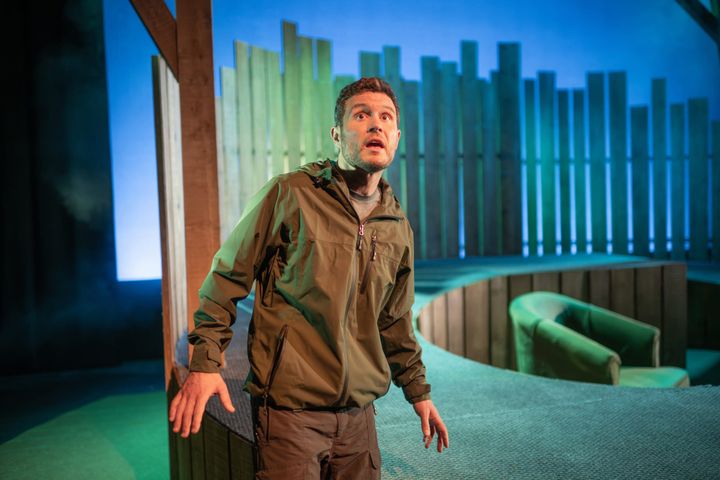 Jordan Young on stage in Man’s Best Friend, green-blue light and timber set.