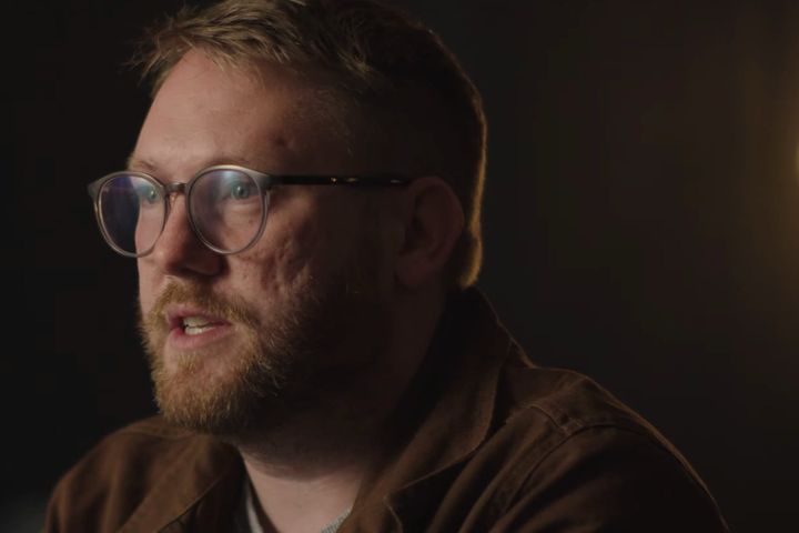Home Alone speaking in a dimly lit interview setting for a short film on Aberdeen’s music scene.