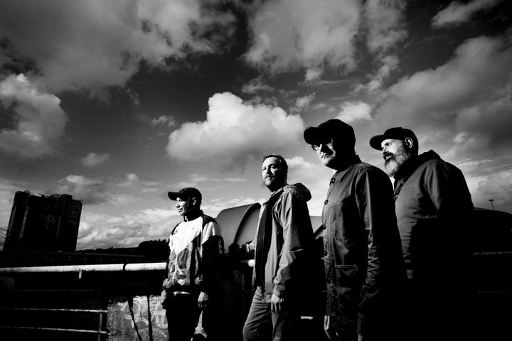 Black and white photo of Mogwai standing outdoors under a cloudy sky.