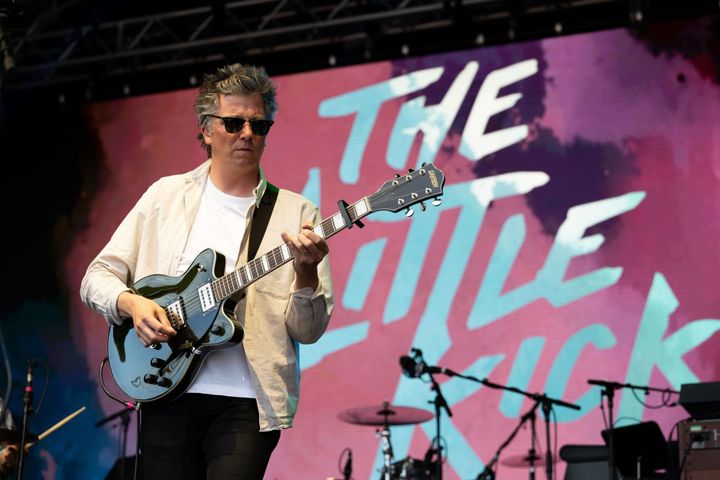Steven Milne plays guitar on stage at The Tall Ships concert, band logo projected in the background.