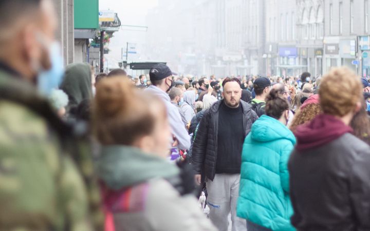 Large crowd filling city street, people in winter clothing walking through Aberdeen City centre.
