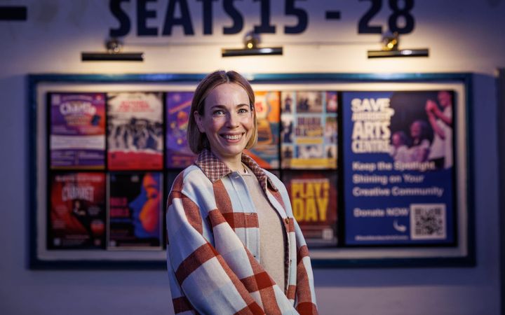 Laura Main standing in front of show posters and the Save Aberdeen Arts Centre campaign poster