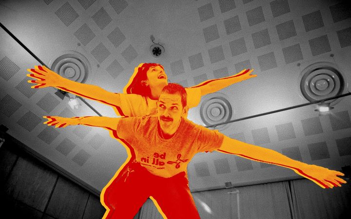 Two young Light the Blue performers, arms outstretched, composited against the Music Hall interior
