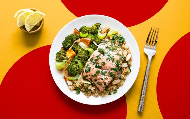 Herb-topped fish fillet with grains, roasted vegetables and lemon on a plate