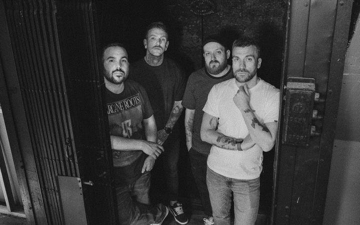 Black and white photo of SUNDRAWN, four-piece band, standing in a doorway