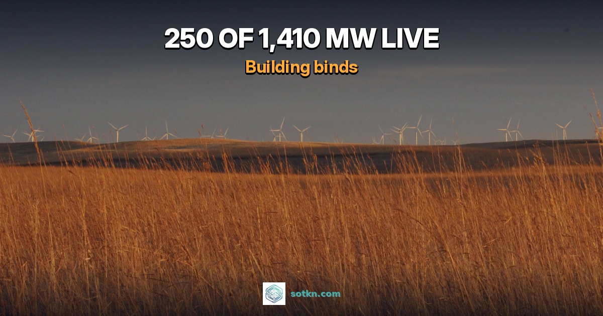 Golden prairie grass under a dark sky with a line of wind turbines on the horizon in Dickey County, North Dakota