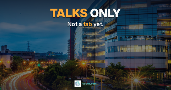 TALKS ONLY. Not a fab yet. A TSMC fab building at dusk with amber headlights on the approach road — discussions confirmed, fab not built.