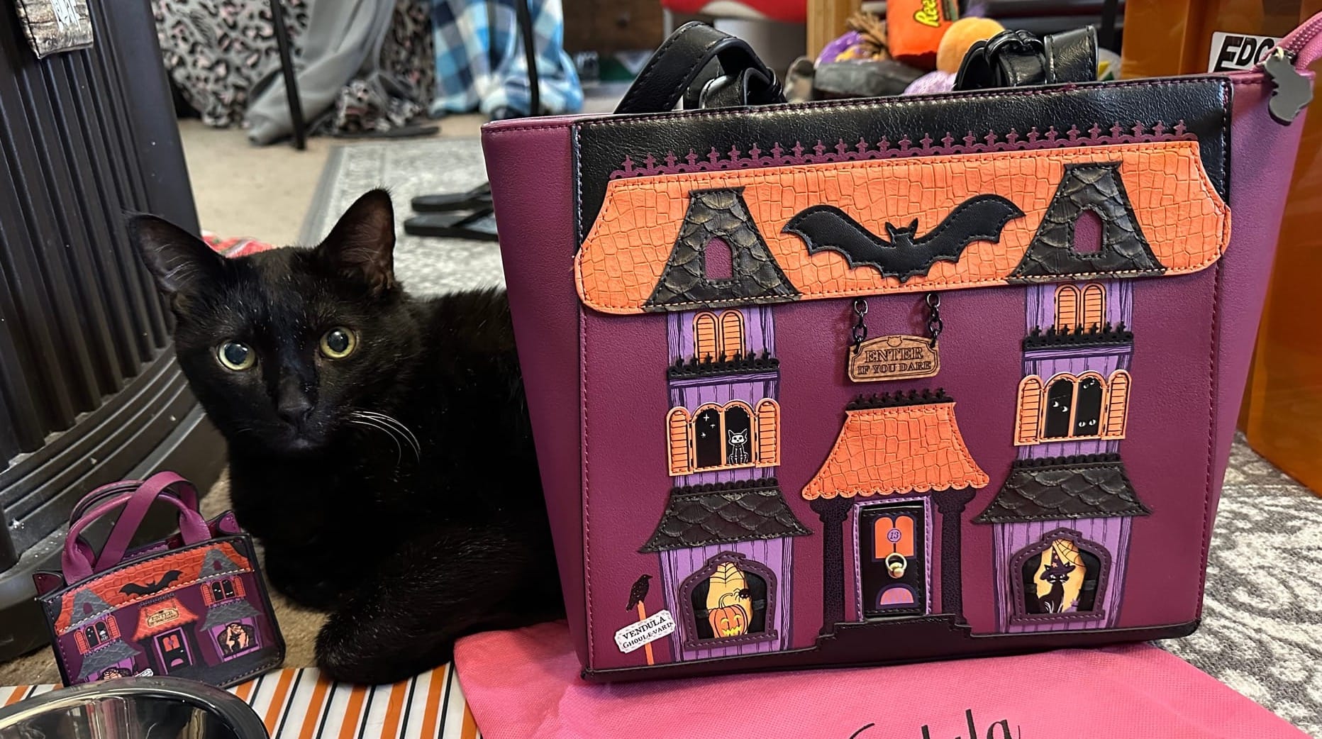 Manny Halloween Cat, a black cat, poses with a Vendula London shopper handbag and key charm.