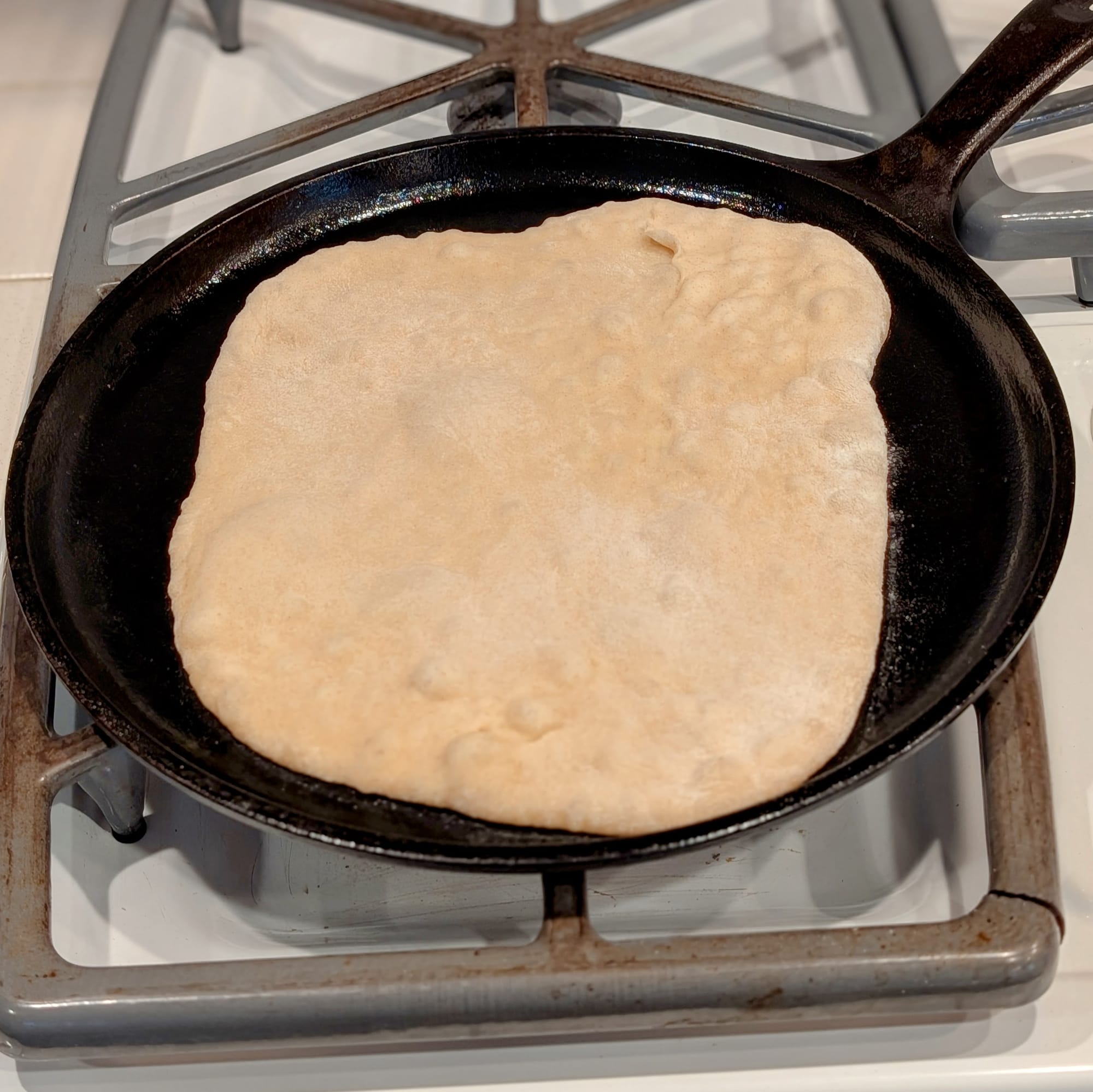 Bonus Pita Bread action shot... a toasty pita just starting to bubble on a hot black iron skillet.