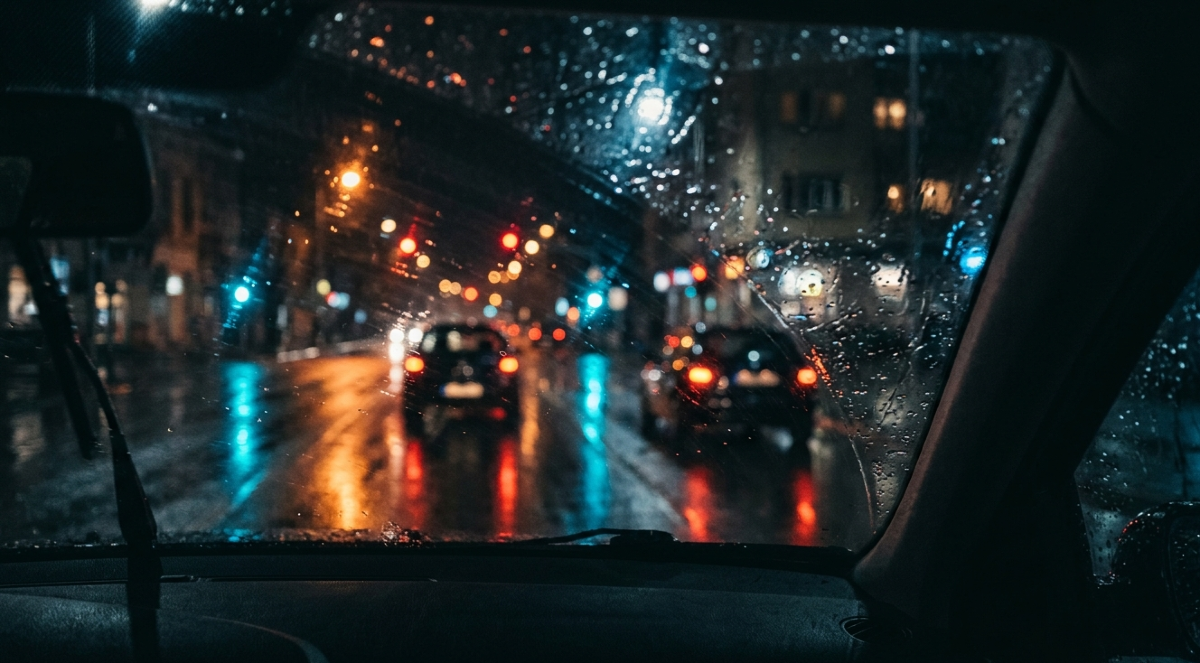 Mokri gradski asfalt noću sa odsjajem svetala, minimalistička urbana estetika.