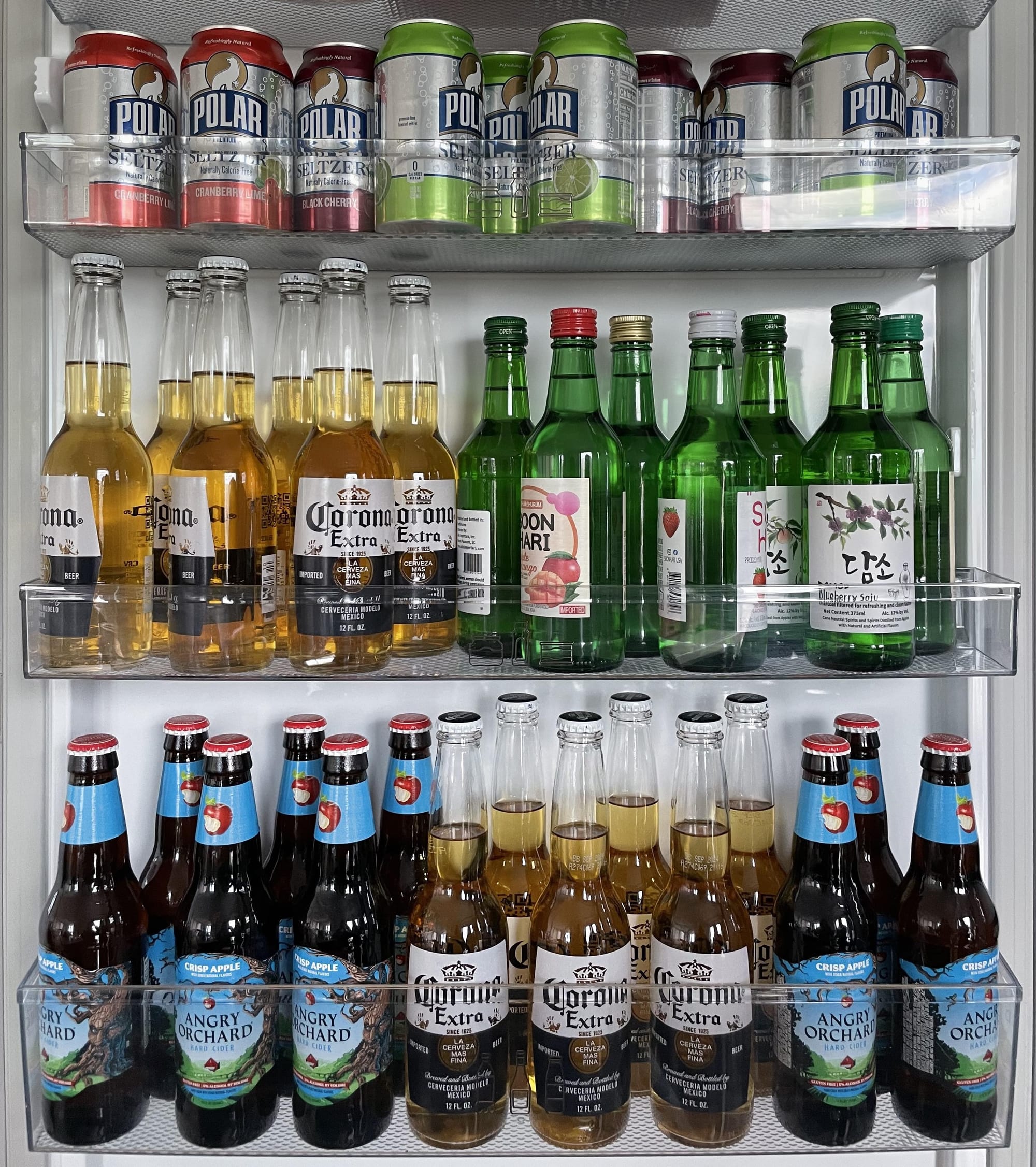 A refrigerator door filled with seltzer, soju, Corona, and hard cider.