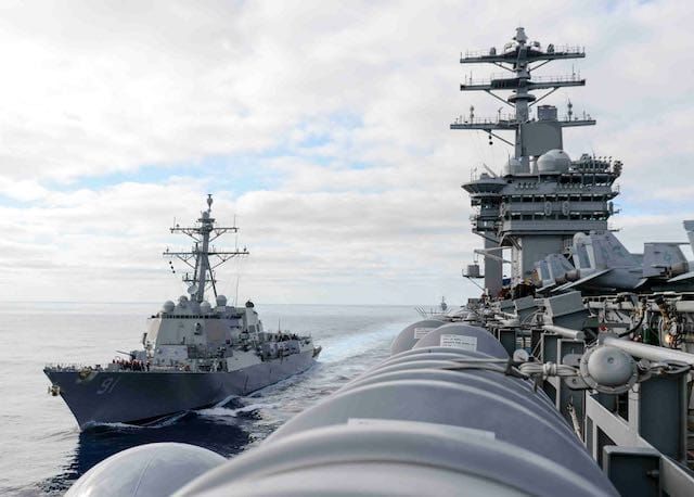 An aircraft carrier and a destroyer steaming side by side.