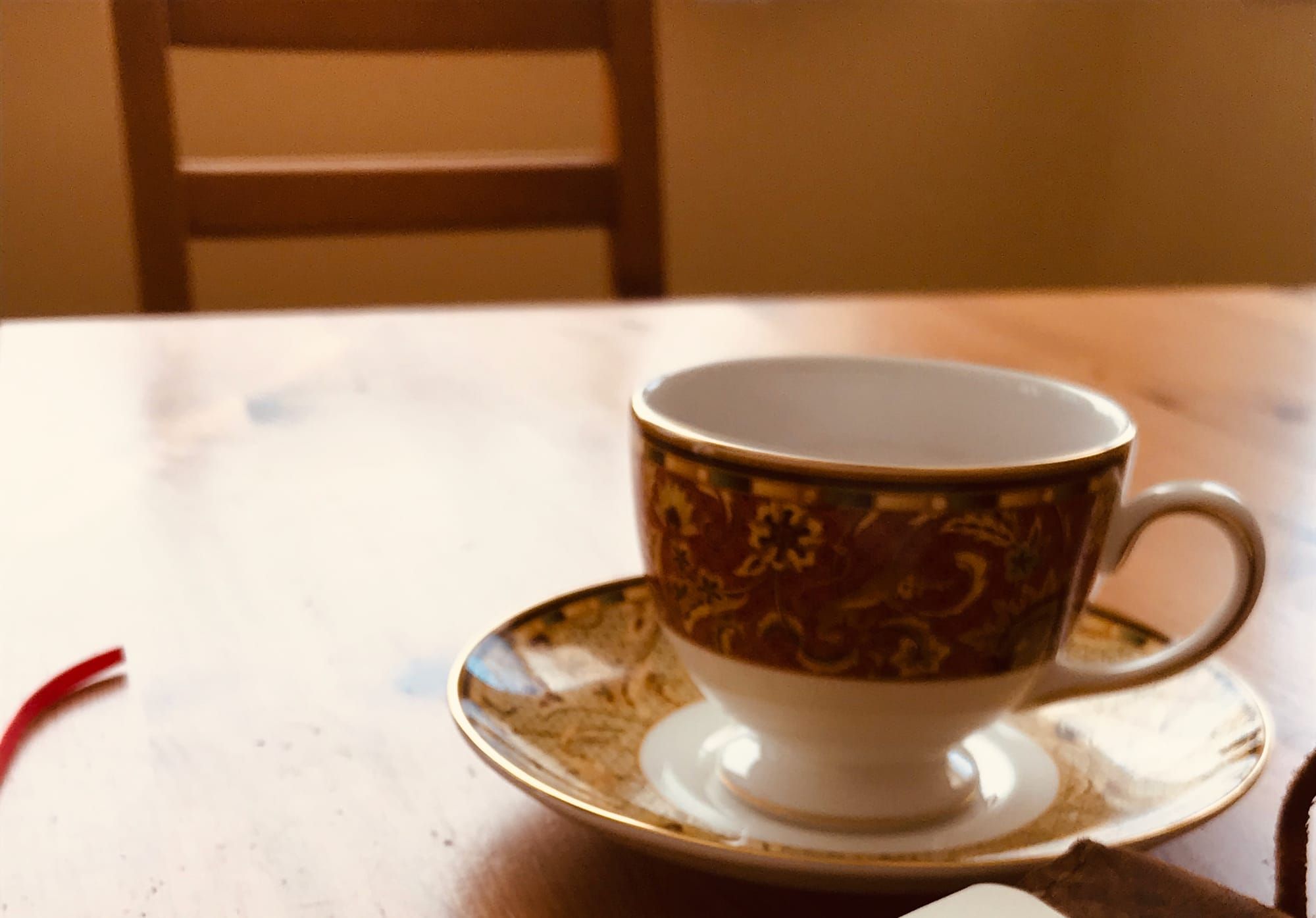 A coffee cup and saucer with Persian designs on a wood table.