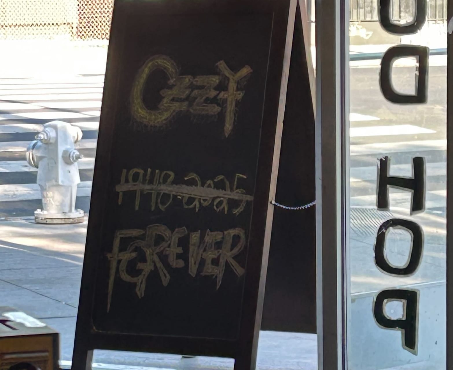Chalkboard sign with “Ozzy” in yellow and “1948–2025” crossed out, replaced with “Forever.”