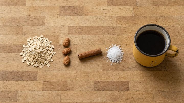 Four loose raw ingredients laid out in a single straight row on a scratched butcher block counter in flat morning window light, shot from directly overhead, with a dented golden yellow ename