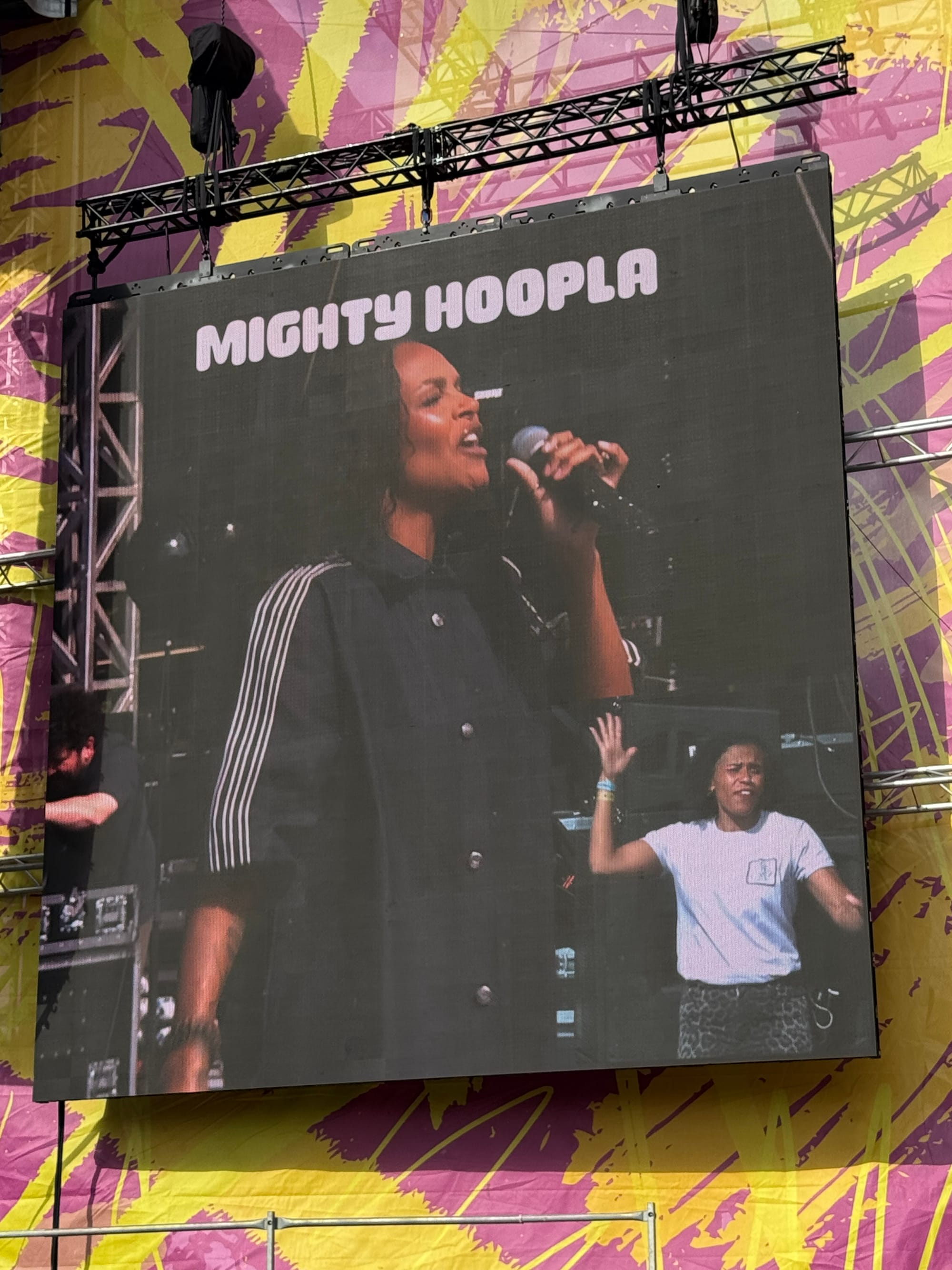 A large screen next to the stage at Mighty Hoopla festival Samantha Mumba is performing in the corner a sign language interpreter signs the song