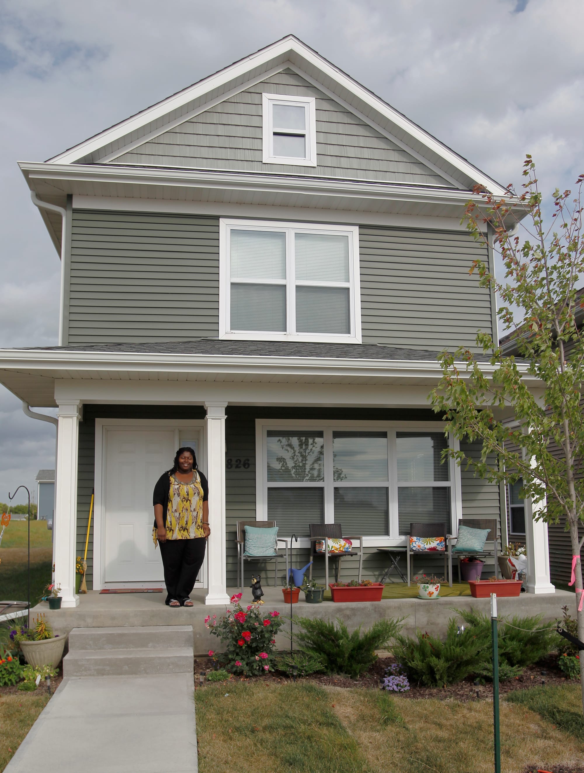 LaTasha Massey stands on the porch of her home on Wednesday, September, 11, 2013 in Iowa City, Iowa. Massey moved in to the house last December participating in a city-run, state-funded program providing down payment assistance to potential home buyers who meet income guidelines.