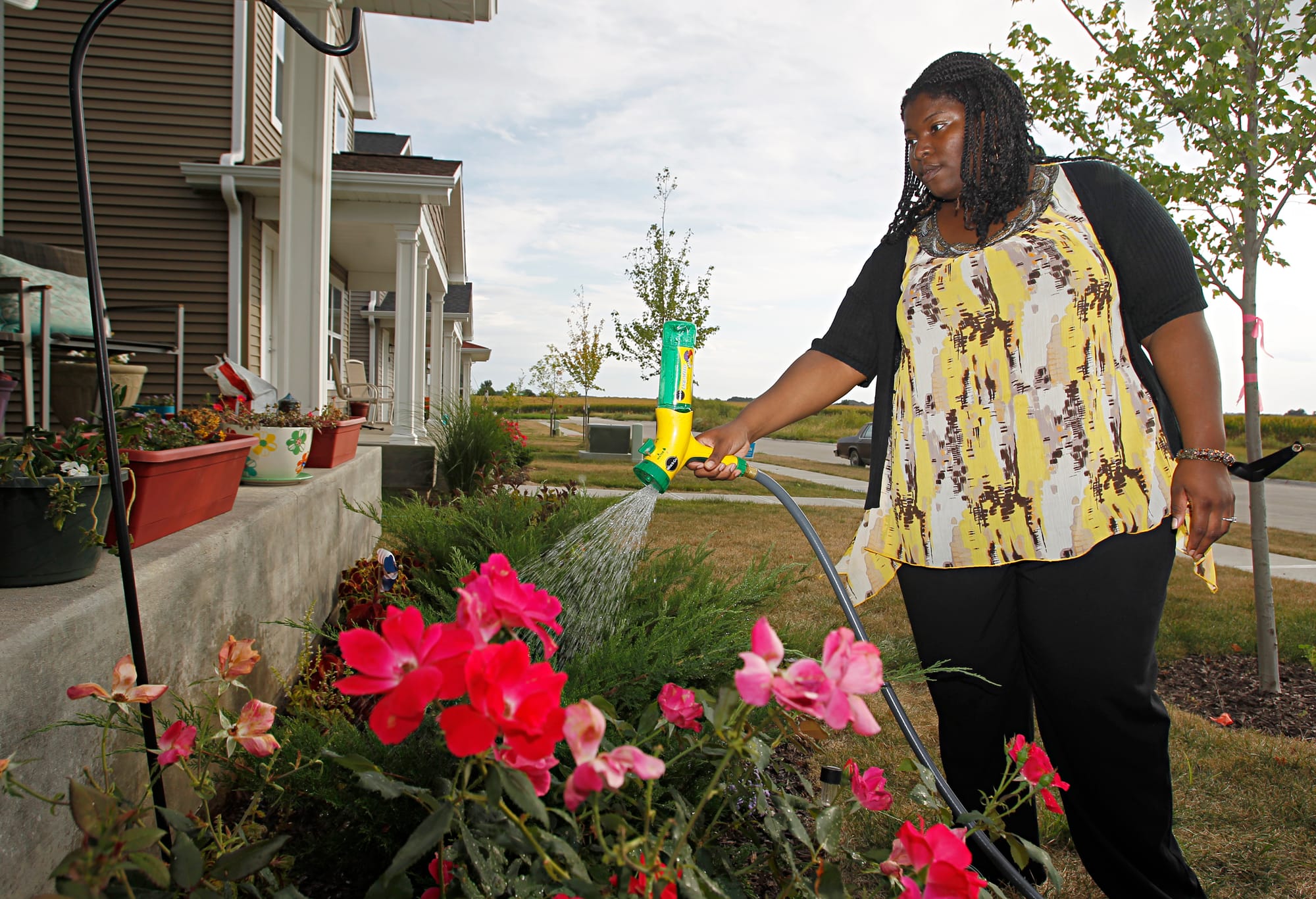 LaTasha Massey waters flowers in her front yard on Wednesday, September, 11, 2013 in Iowa City, Iowa. Massey moved in to the house last December participating in a city-run, state-funded program providing down payment assistance to potential home buyers who meet income guidelines.
