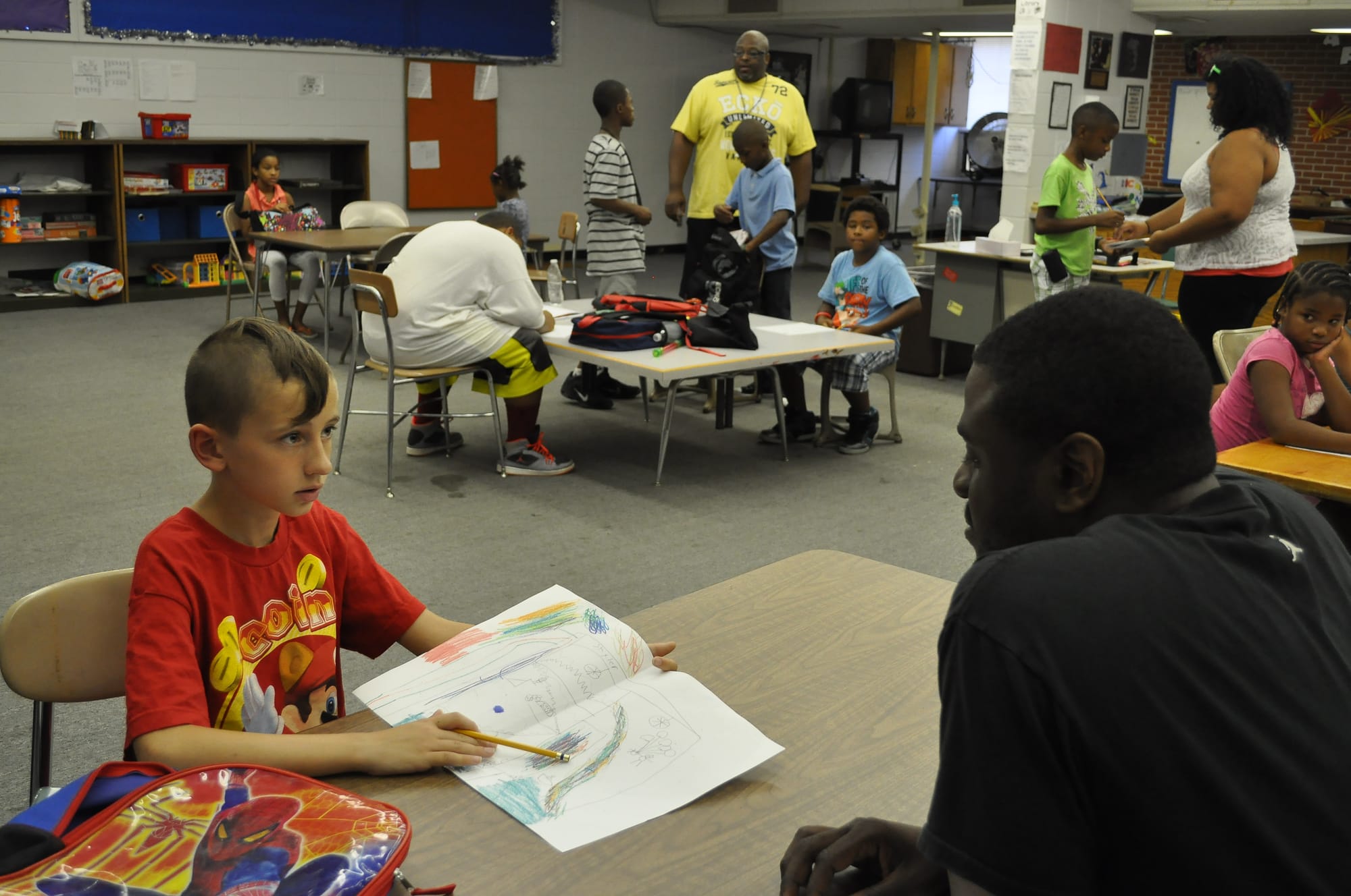 Skyler Weilenman, a fourth-grader from Fort Dodge, shows a drawing to Charles Clayton during the AFES after-school program. The program reaches out to students of all races and economic backgrounds to help keep them engaged in their schoolwork. 