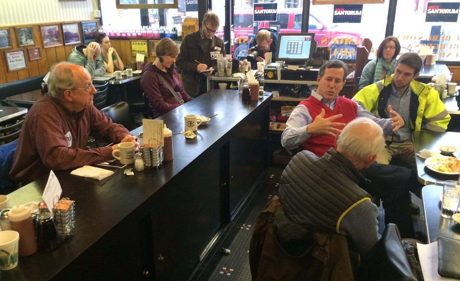 Bill Warner (left at the counter) of Coralville and Republican presidential candidate Rick Santorum exchange views about gun violence during a Santorum campaign stop at Iowa City's Hamburg Inn restaurant the morning of Jan. 25, 2016.