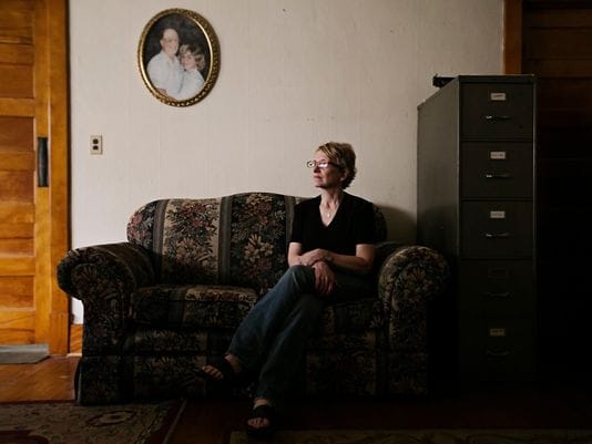 Jody Ewing at her home in Onawa on Thursday, June 25, 2015. Ewing is the founder of Iowa Cold Cases, a website dedicated to cold cases around the state. Originally started as part of a reporting project, Ewing found herself in shock when she had to put her own father, pictured in the portrait above her, on the website after he was killed in an explosion.