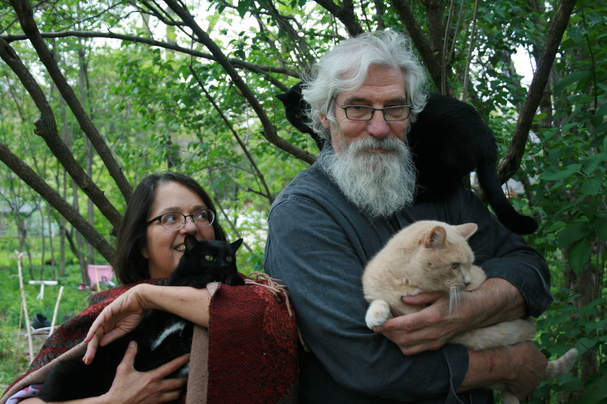 Rebecca Rosenbaum and her husband, Steve Marsden pose with their cats in the backyard of the Iowa City home.