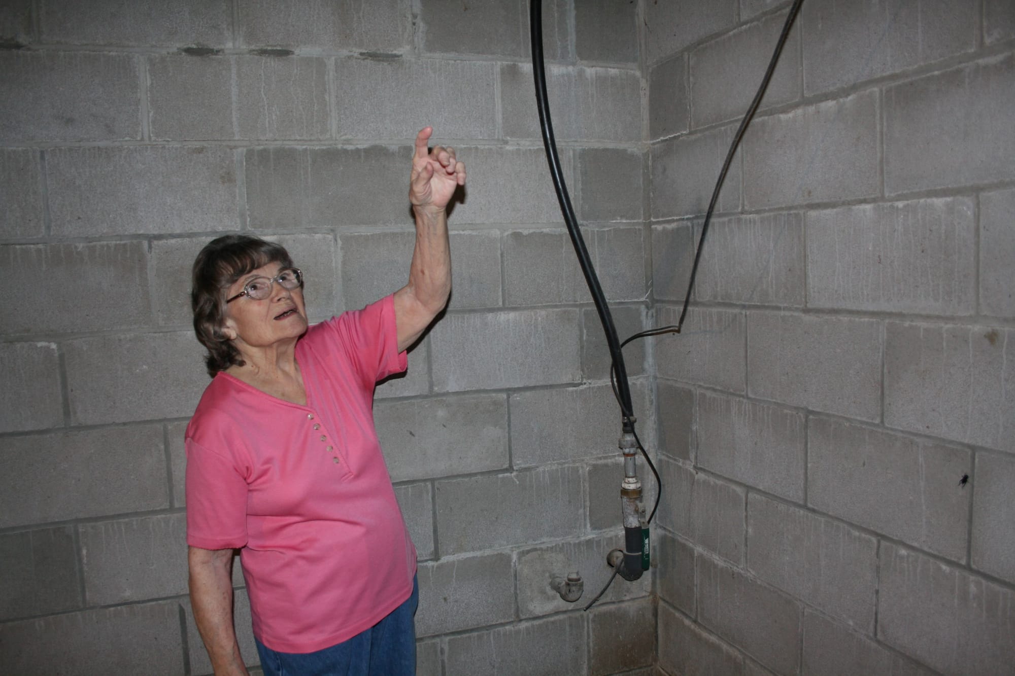 Joan Michels, of Earling, Iowa, points to the water lines coming in her house from the well outside. Michels said she didn’t know the exact age of the well, but it was there since at least the 1950s. Her husband first brought the water lines into the house in the 60s, before that the house had no running water. Photo taken Aug. 19, 2016.