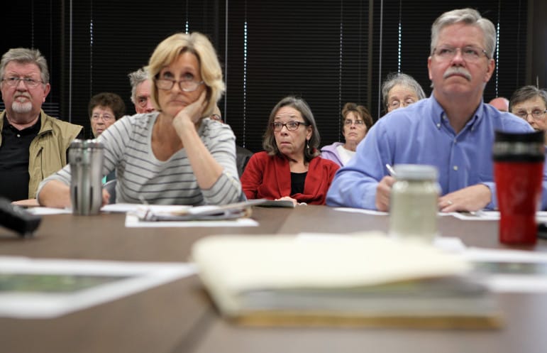 Kathy Kachel (center), a Wisconsin homeowner whose house overlooks Pattison SandÕs Iowa operations, reacts to testimony given by professor Patrick O'Shaughnessy at a meeting of the Mine Reserve Expansion Study Committee. In the foreground are commitee members Anne Osmundson and Tom Blake.