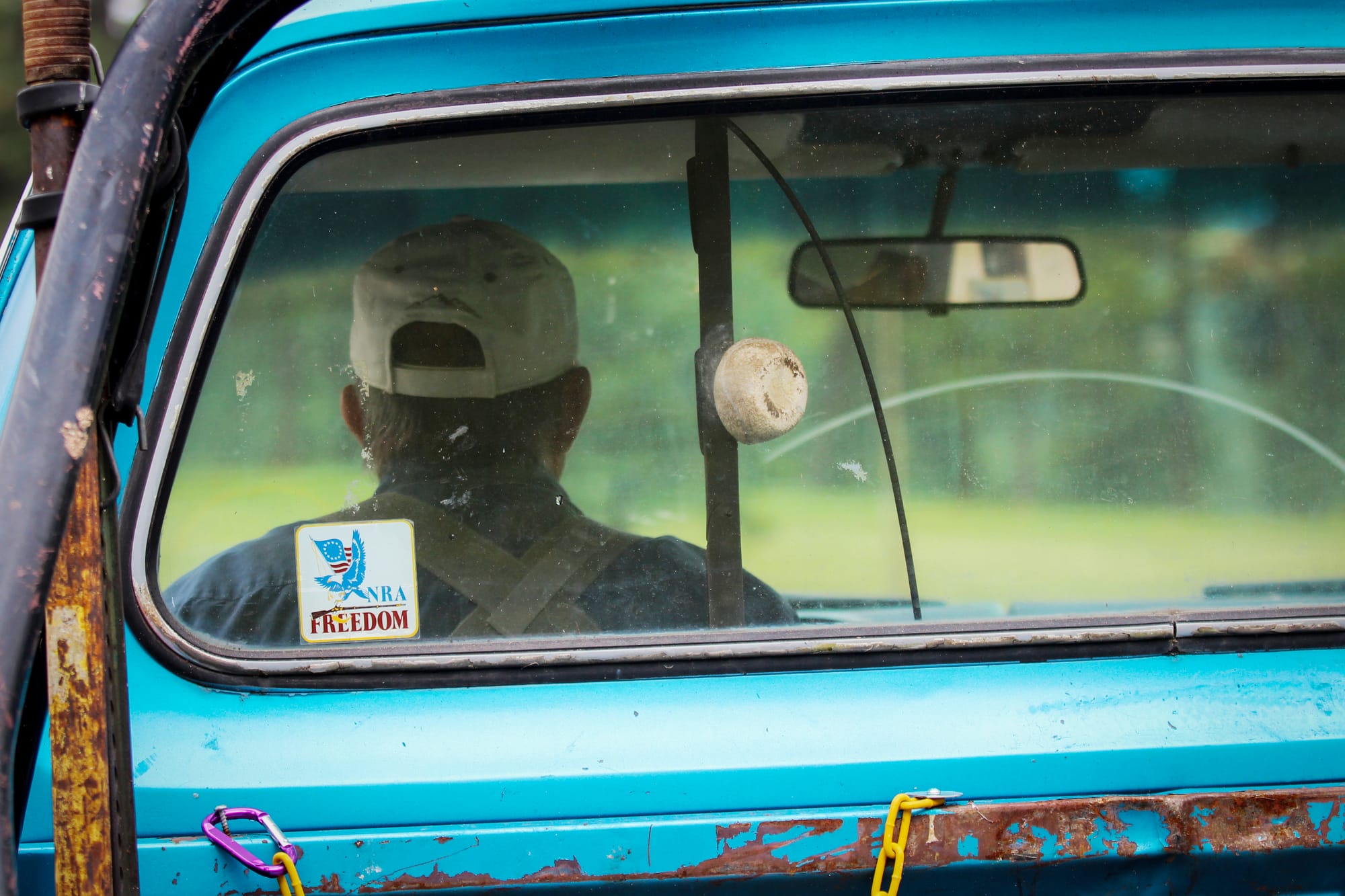 Gary Marbut drives into the woods surrounding his house in his blue pickup. The truck has red and white stripes and a National Rifle Association bumper sticker.