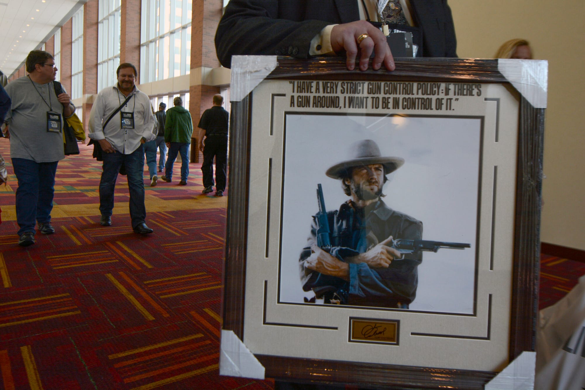 An NRA member carries a framed picture of Clint Eastwood from the exhibit hall at the group’s 143rd annual convention.