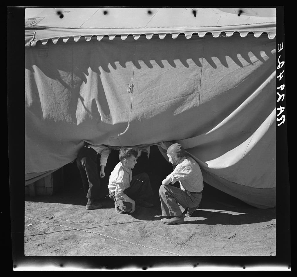 Boys sneaking under a circus tent in Roswell, New Mexico in 1936.