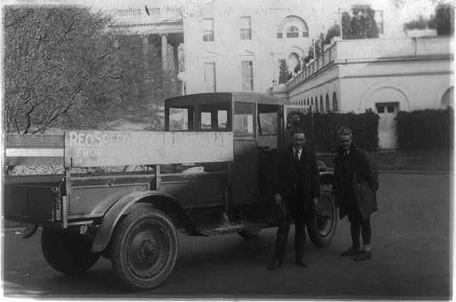 Two men standing next to a Reo truck in 1922.