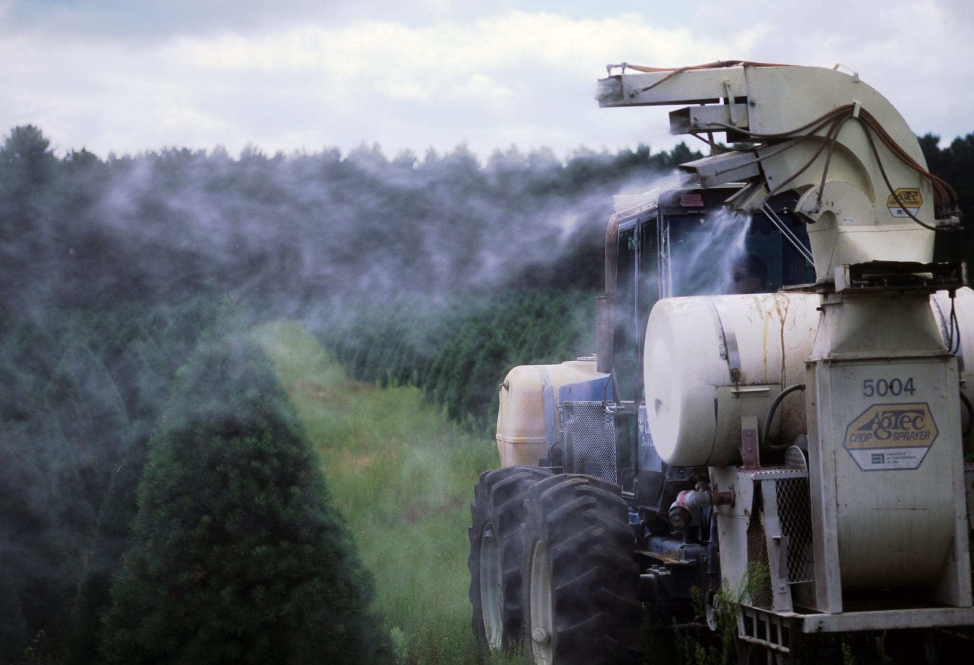 Machinery sprays pesticide on rows of Christmas trees at a tree farm near Wautoma, Wis.