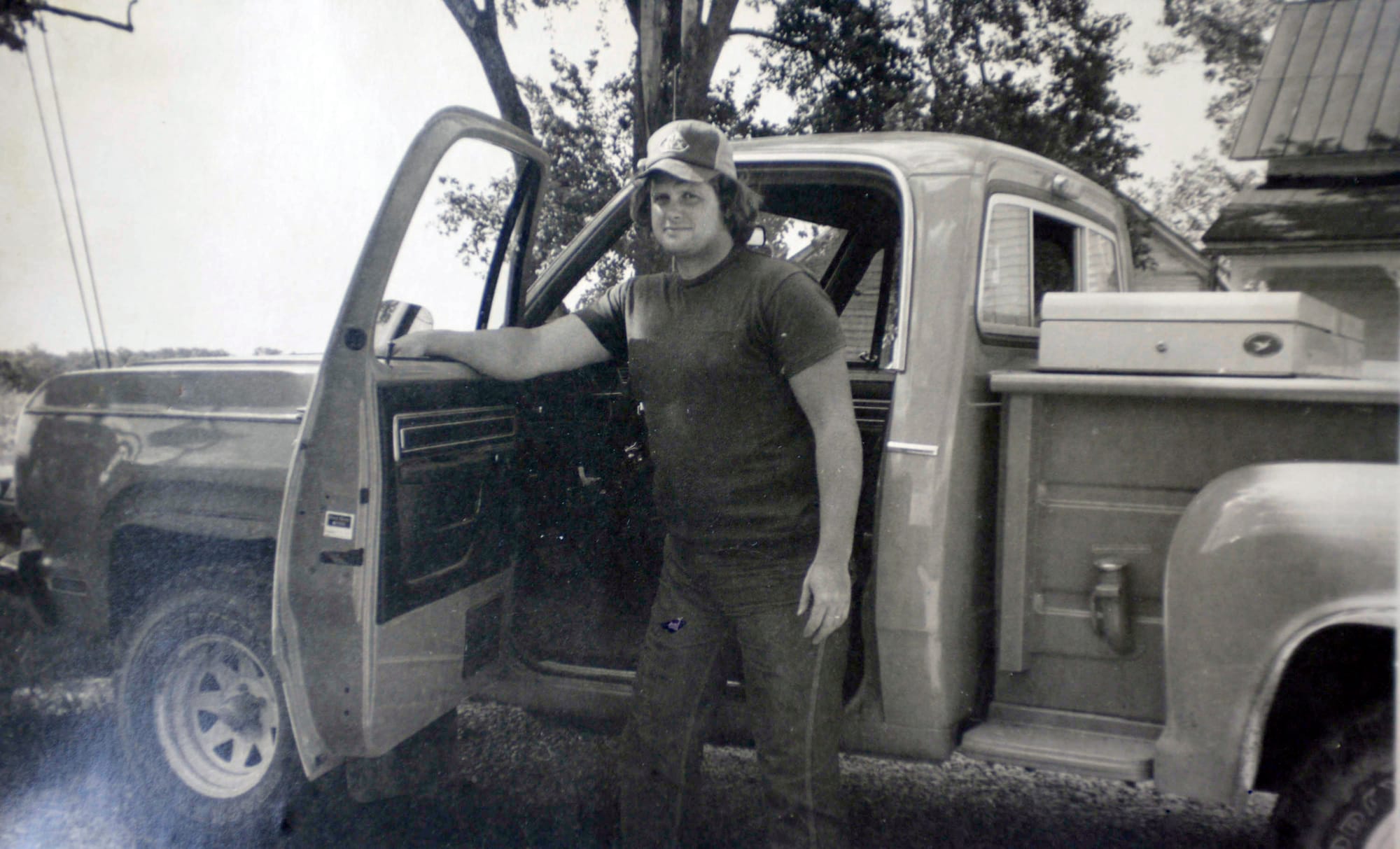 A young Chip Petrea stands next to an old truck parked outside.