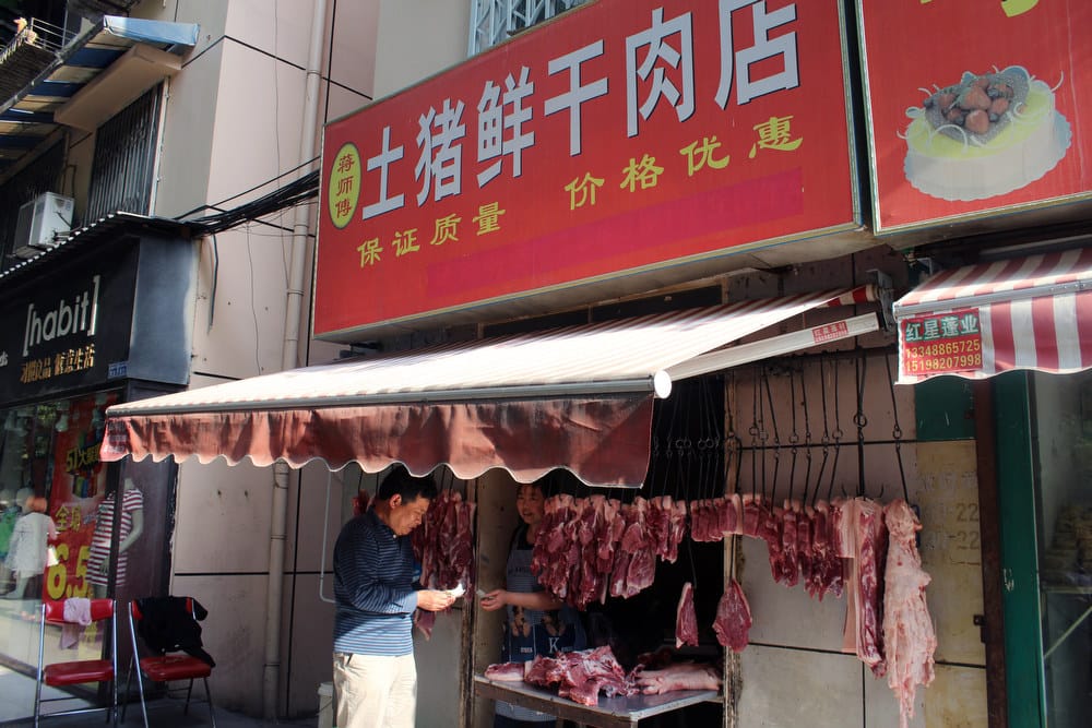 A person stands near a meat store at a market in the city of Chengdu in southwest China. In 2013, China accounted for 16 percent, or $14.4 million, of Tyson’s international chicken sales.