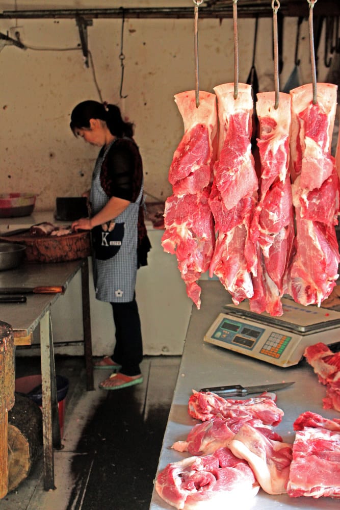 A woman stands at work in a market the city of Chengdu in southwest China. According to experts, meat production in China has been rising for parts of three decades.