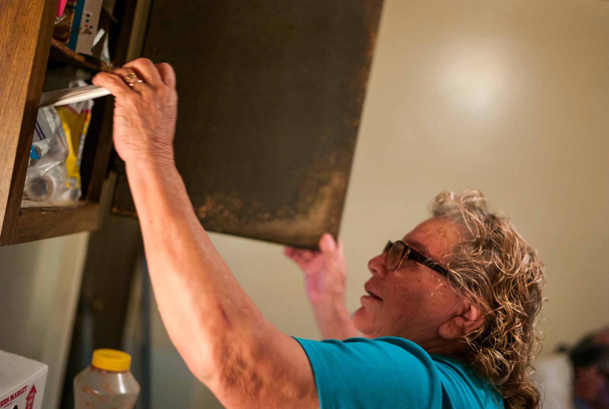 Leonor Pizana reaches into a kitchen cabinet at her apartment at the Pine Creek housing facility for migrant farmworkers in Holland, Michigan.
