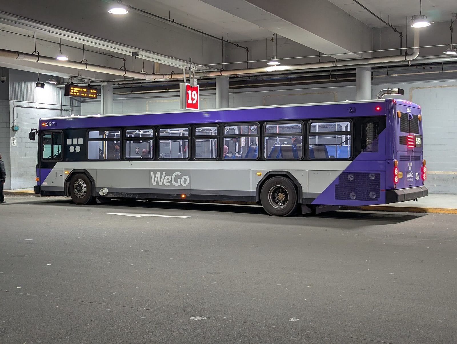 A purple and silver WeGo bus inside a transit center bay