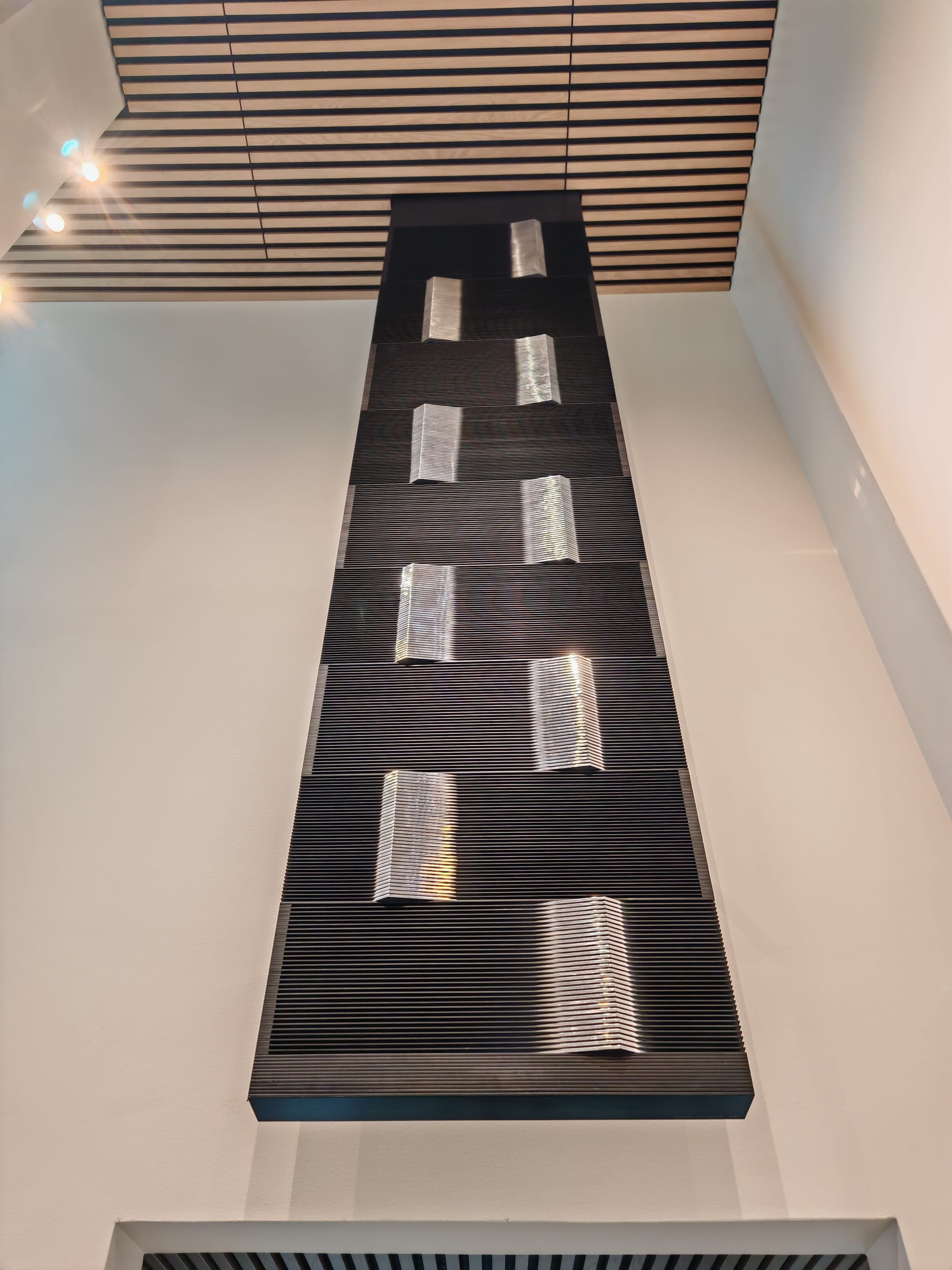Modernist sculpture by Raimo Utriainen positioned in the stairway; a sleek, vertical form in metal, bridging space and structure.