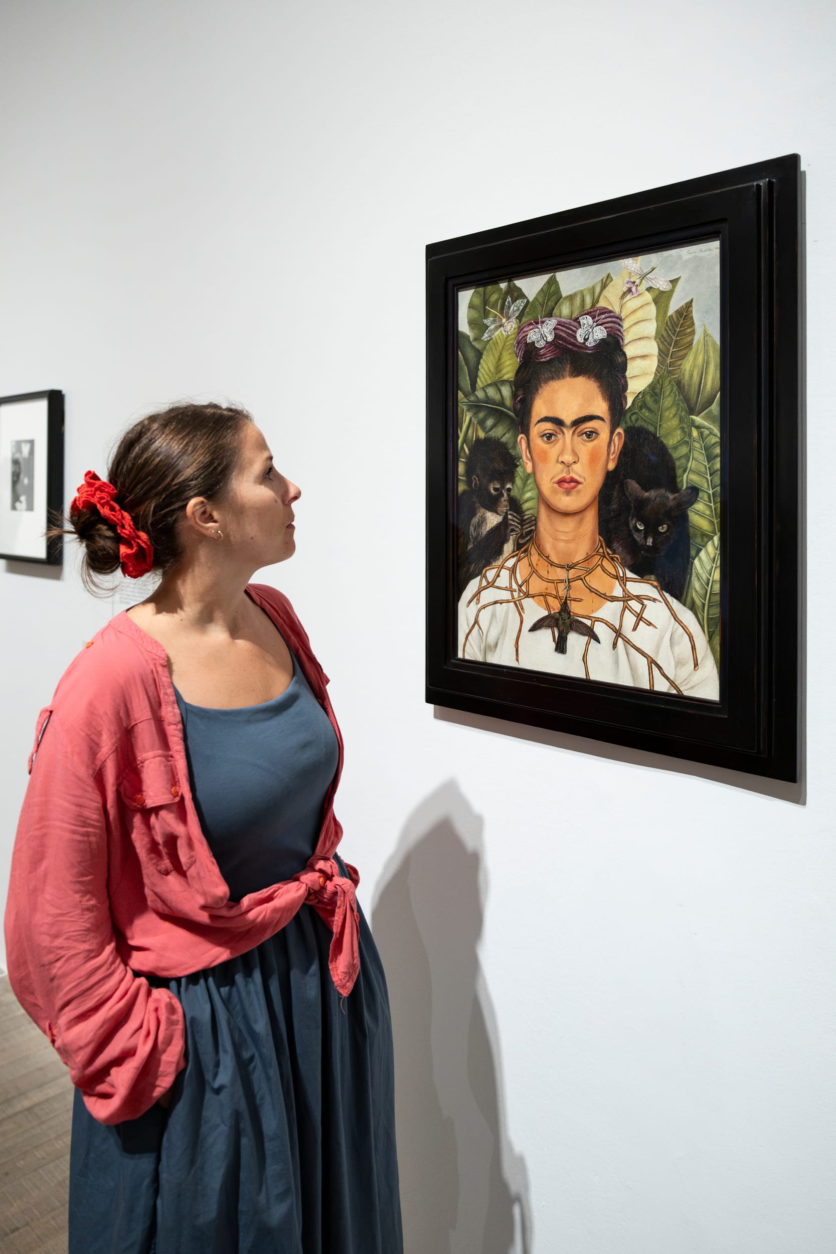 A visitor stands close to Frida Kahlo’s Self-Portrait with Thorn Necklace and Hummingbird in a Tate Modern gallery.