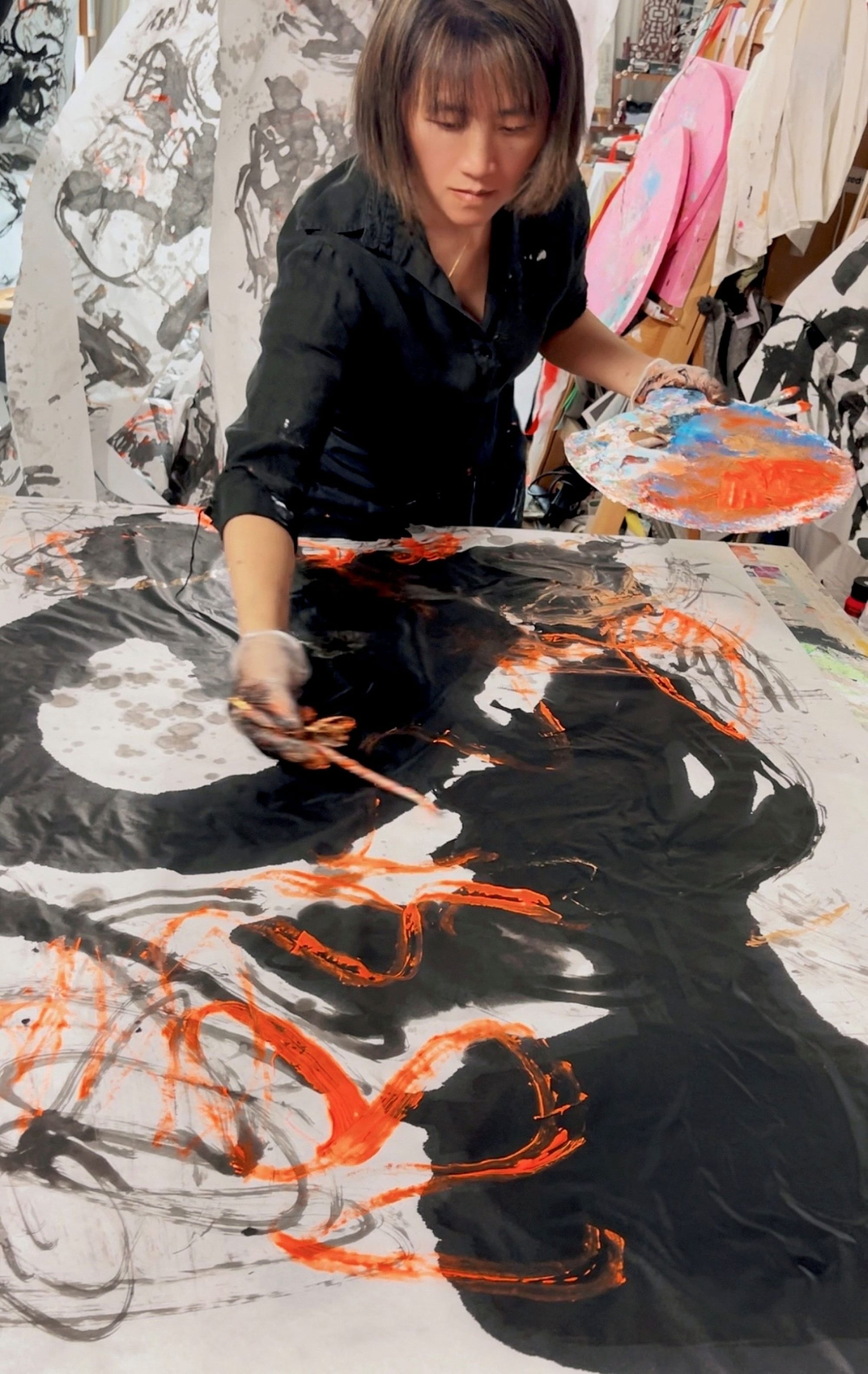 Canal Cheong Jagerroos in her Helsinki studio, seated near works and materials that reflect the layered process behind her mixed-media paintings.