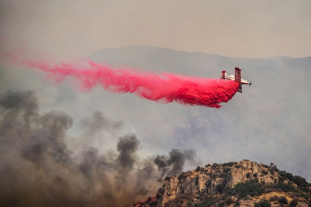 A firefighting plane releases fire retardant over raging flames in the Los Angeles hills.