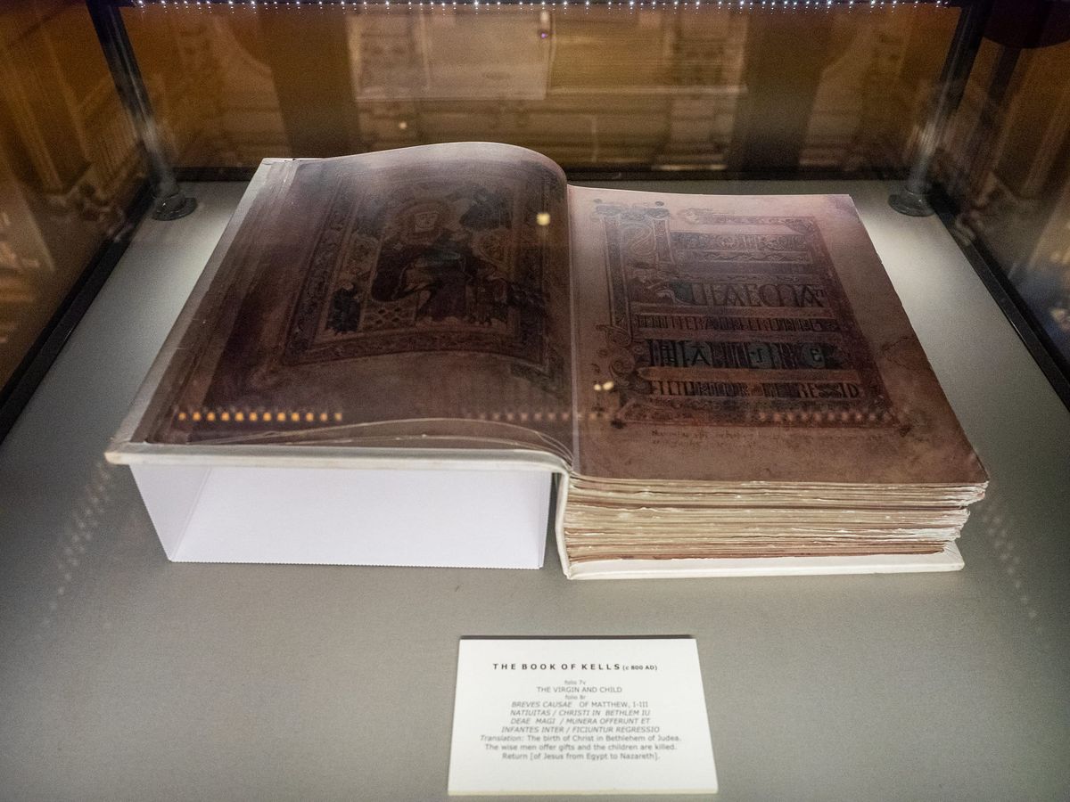 Illuminated page from the Book of Kells with intricate interlace and display capitals, photographed at Trinity College Dublin