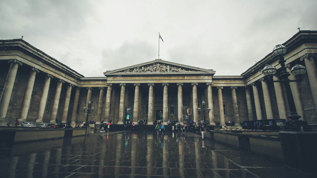 The British Museum’s neoclassical façade under grey London light, with visitors moving across the stone forecourt.