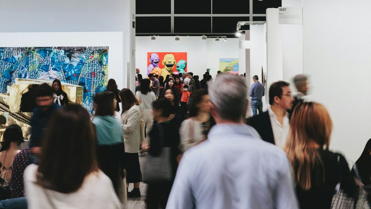 Collectors and visitors viewing artworks in an art fair, representing a selective art market shaped by provenance, rarity and defensible value.