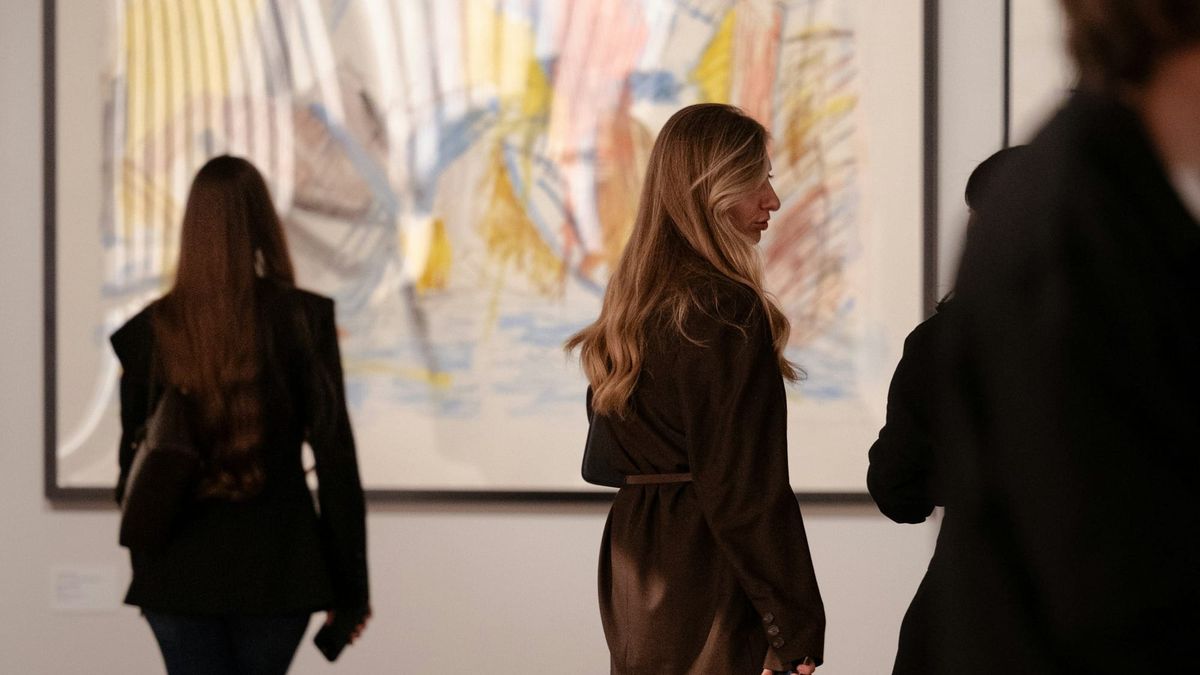 Visitors viewing contemporary artworks in a gallery setting, representing young artists, market visibility and the gap between attention and liquidity.
