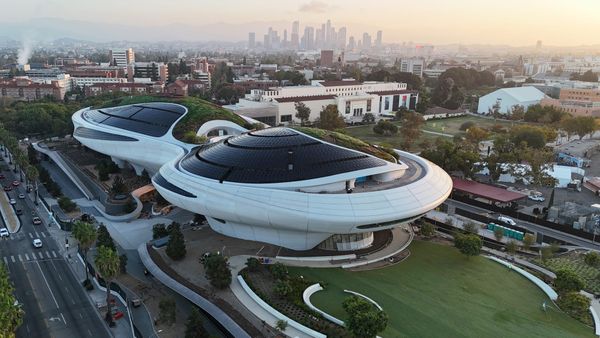 A sweeping aerial view of the futuristic, curved Lucas Museum of Narrative Art rising above Los Angeles’s Exposition Park.
