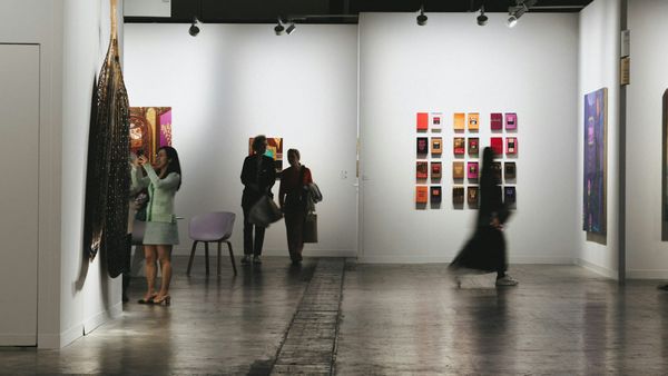 Collectors and visitors viewing artworks in an auction preview or art fair setting, representing a concentrated top-end art market shaped by buyer readiness and selective demand.